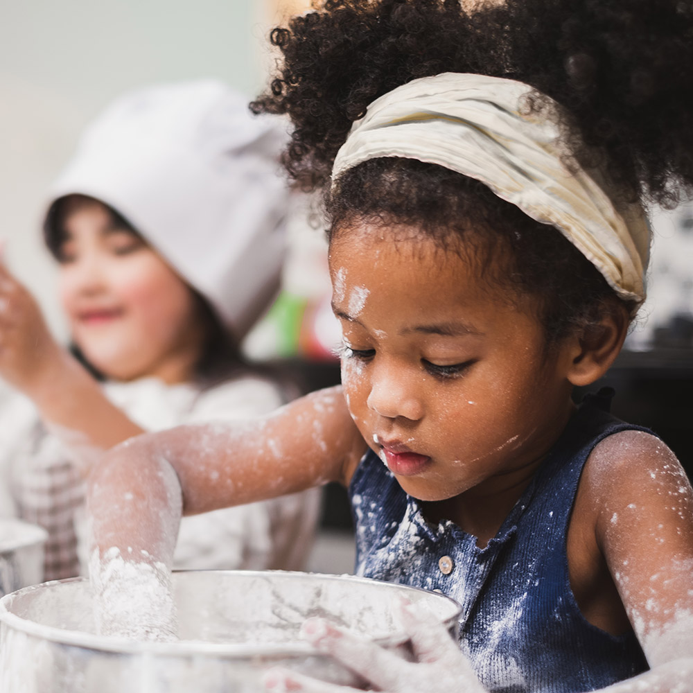 two girls cooking during at a sticky fingers cooking birthday party